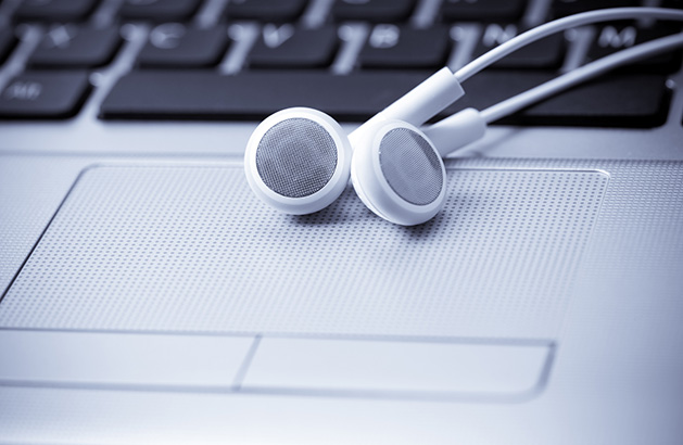 A pair of white headphones rest on a laptop.