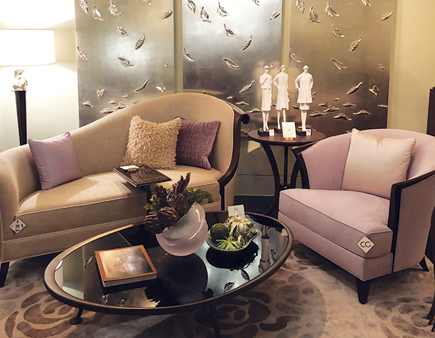 A living room remodeled by Jayne Morrison Interiors, featuring a tan sofa with purple and tan throw pillows, a purple chair, a glass top coffee table and many accent pieces.