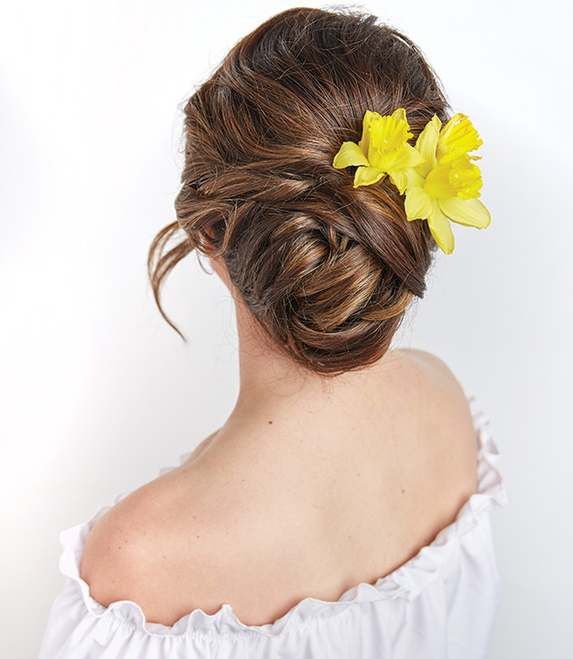 A woman with a yellow flower in her hair models a hairstyle from Christopher J Salon.