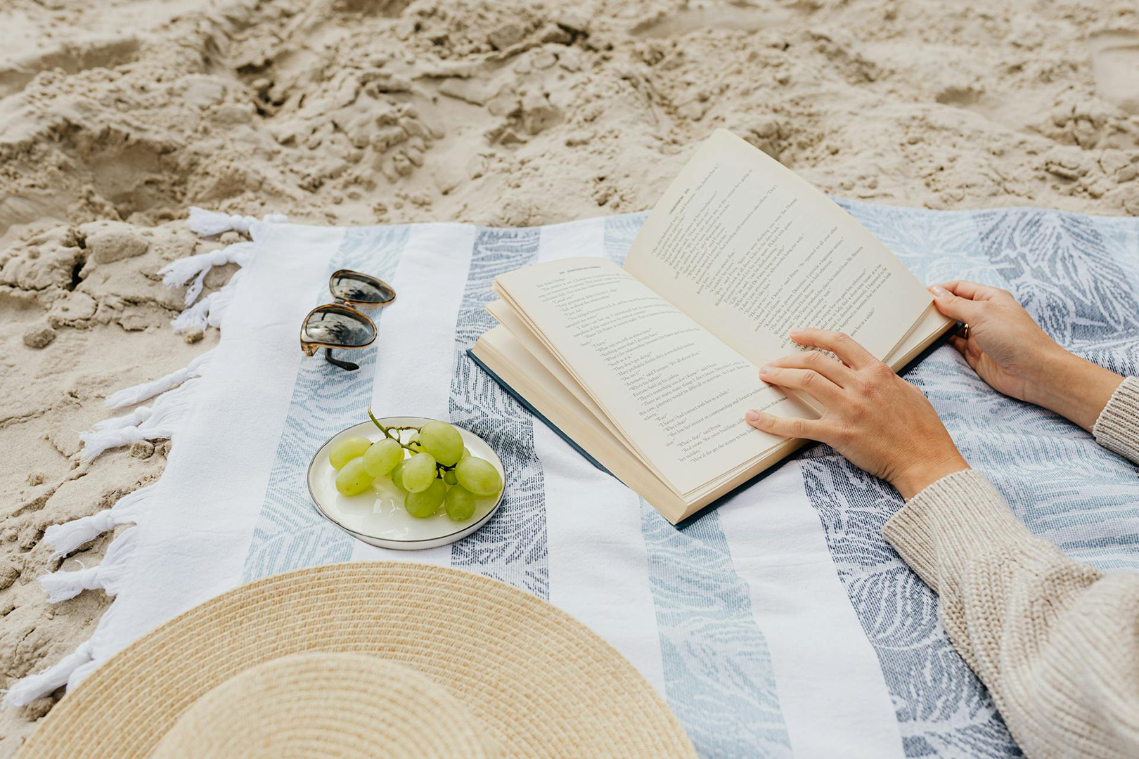Person reading on a blanket at the beach