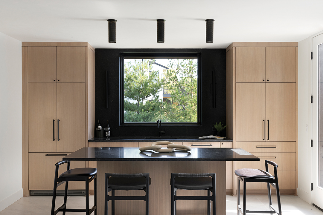The backsplash of this lower level bar uses the same granite as the countertops. “It’s got a very faint, warm beige veining that goes throughout,” Lindsey Swanson says. The black monopoint lights above the island contain small openings that diffuse light. “It adds texture in a way that’s a little bit different,” Swanson says.