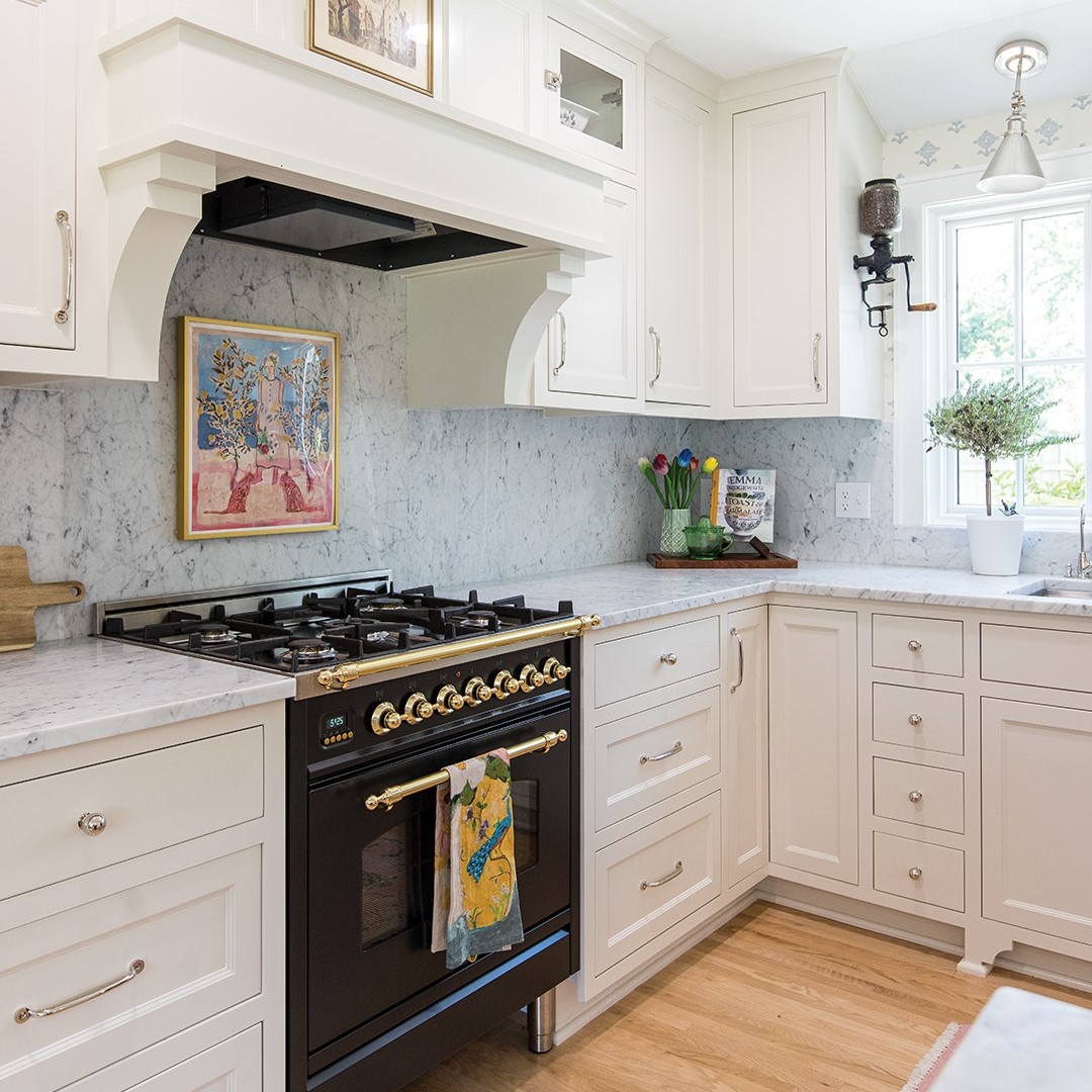 “I imagined a cottage kitchen with a French bistro feel, and that became my starting point,” Andrea Soule says. “Soft beige cabinets, marble countertops, an Italian Ilve range, an antique coffee grinder, faded blue-and-white wallpaper, wicker baskets, fresh flowers and an antique gold chandelier bring the whole space to life.”