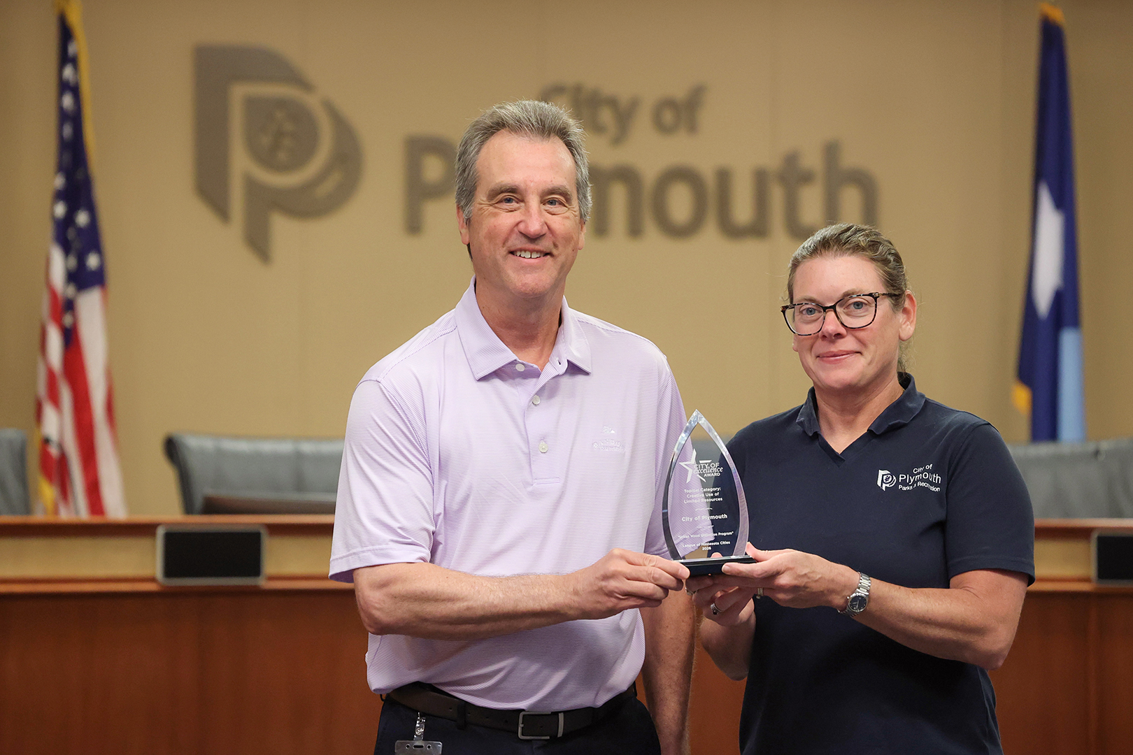 Plymouth’s city manager Dave Callister (left) and parks and recreation director Jennifer Tomlinson (right) holding the City of Excellence Award awarded by the League of Minnesota Cities for its Urban Wood Utilization Program.